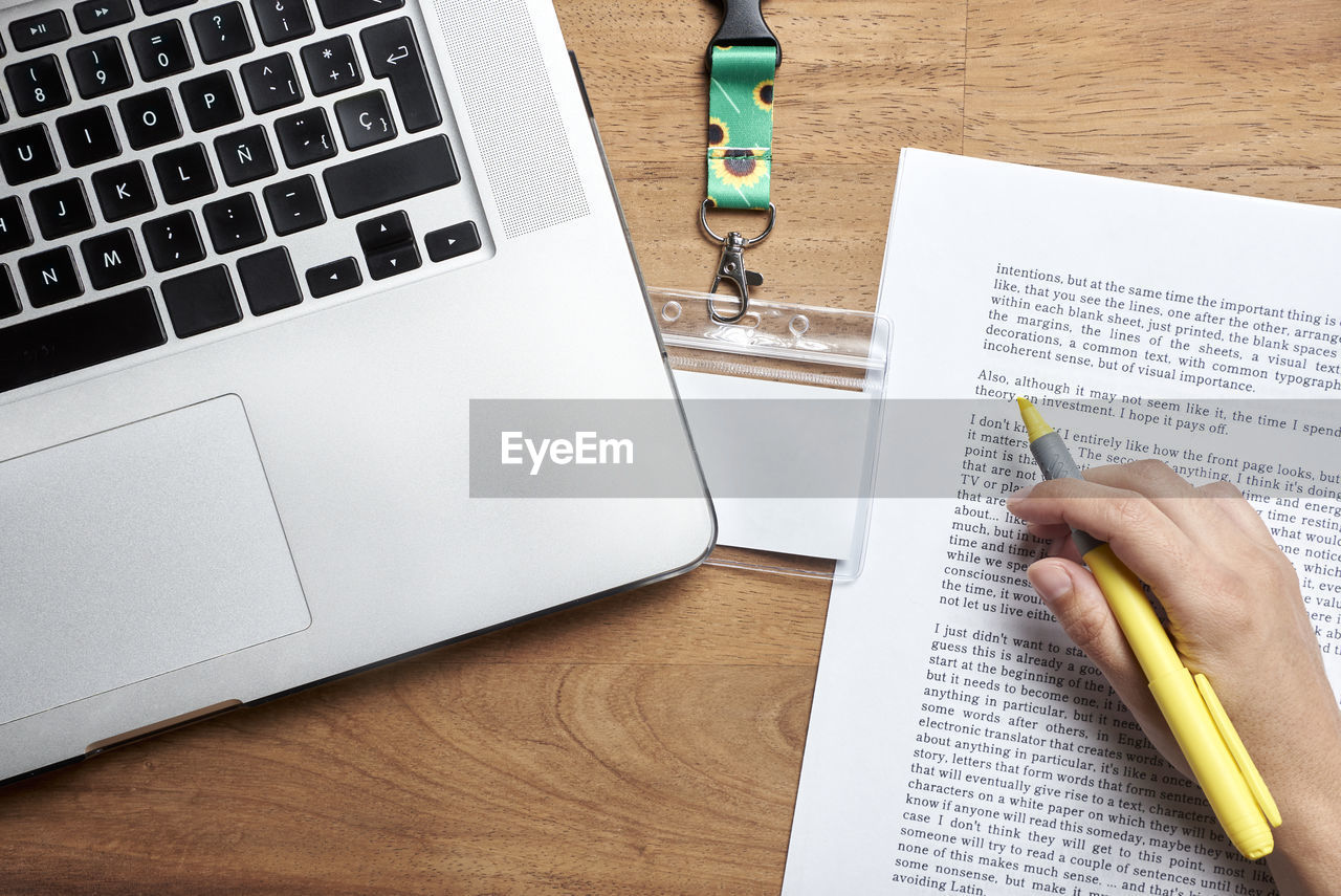 cropped hands of woman writing in book on table