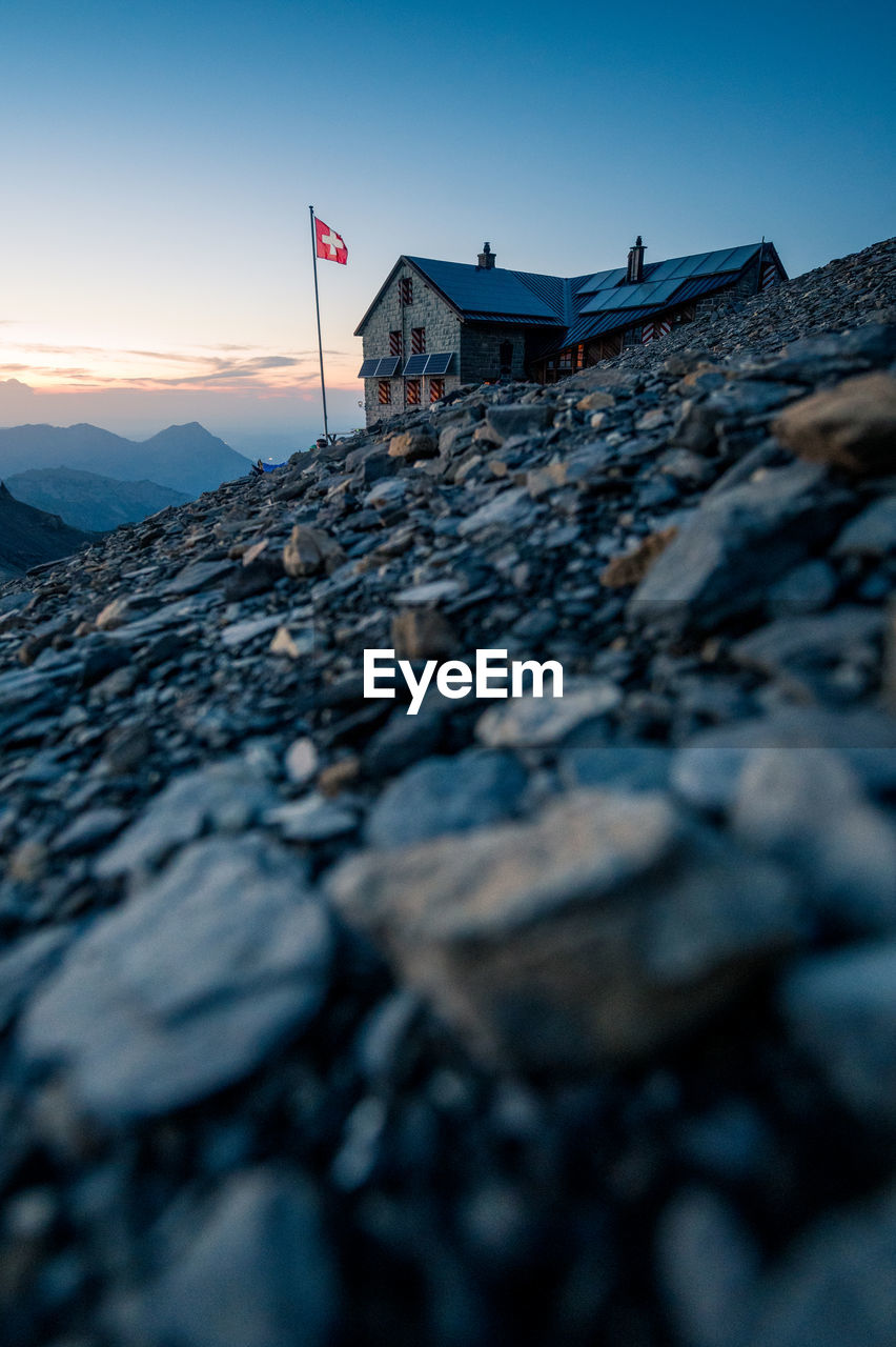 Surface level of land against house and sky during sunset