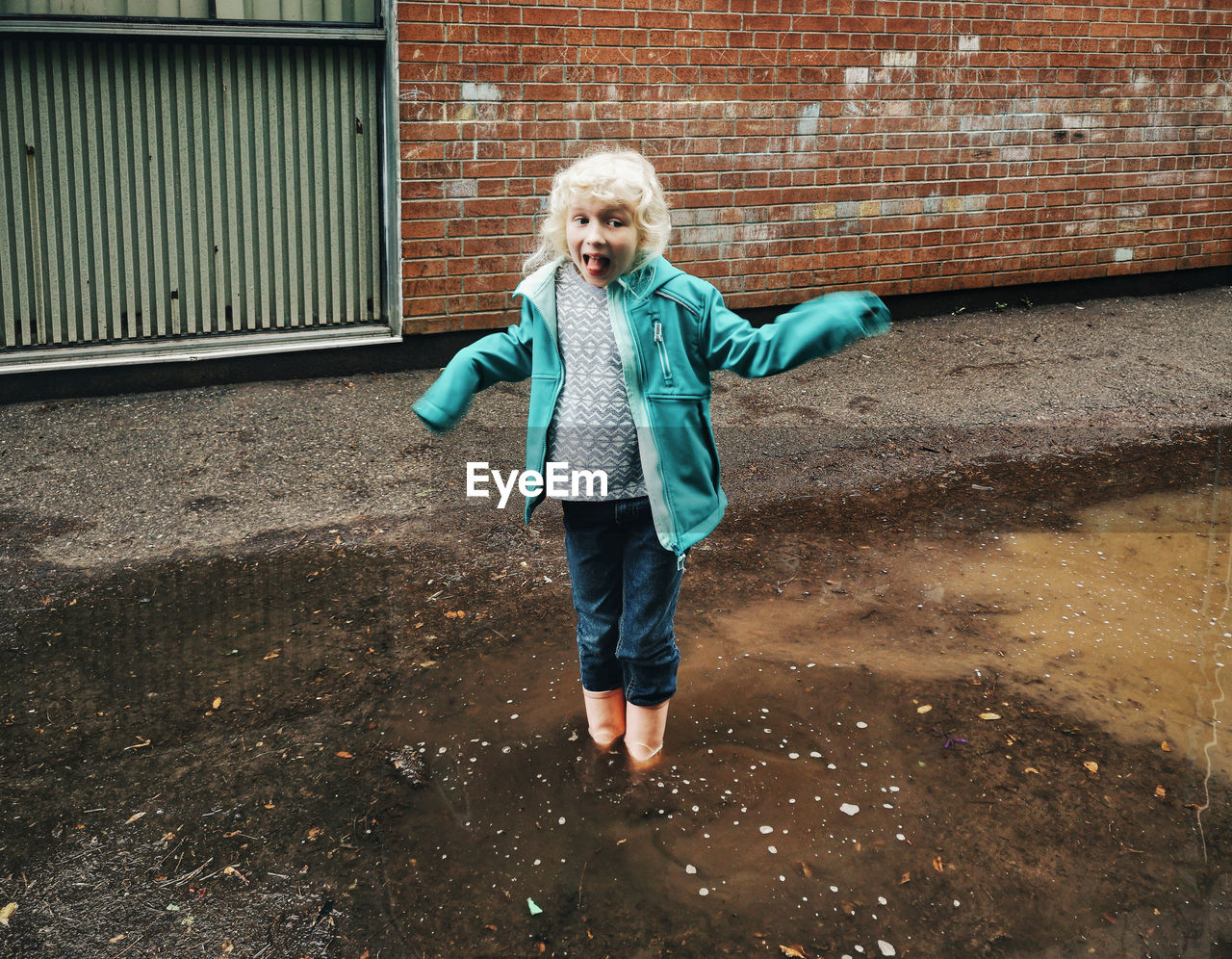 Girl standing in dirty puddle against wall