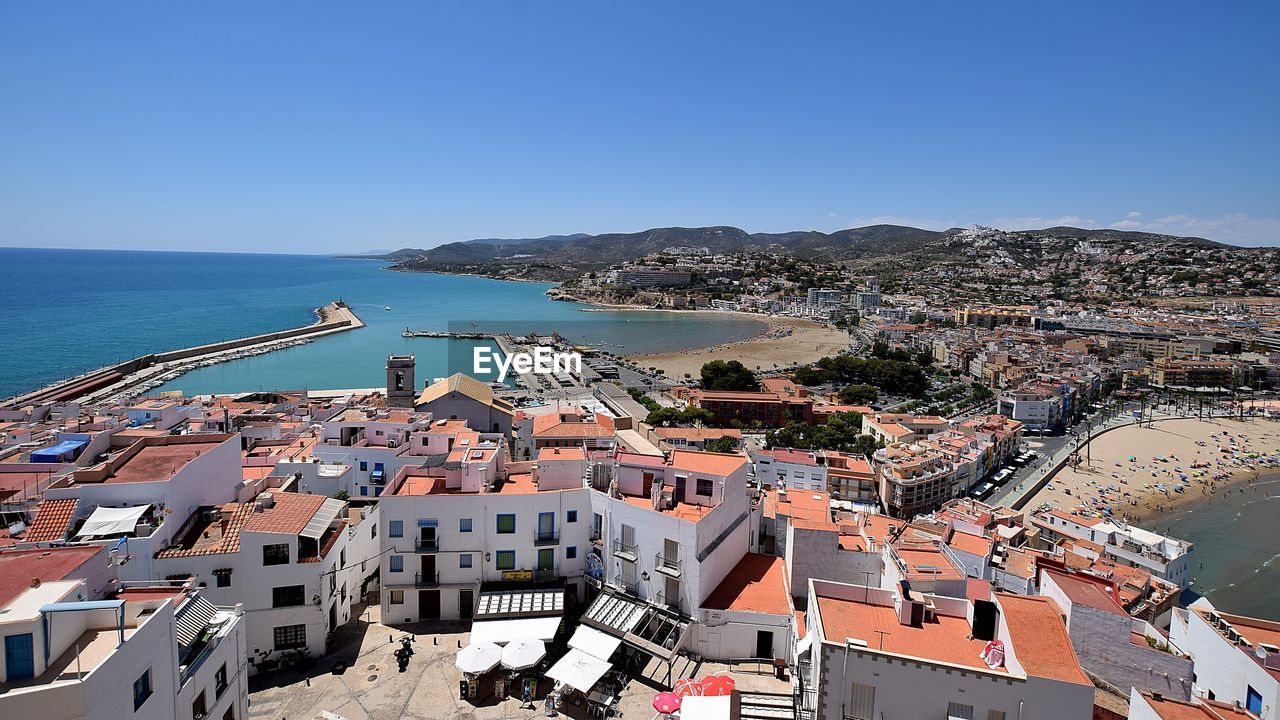 HIGH ANGLE VIEW OF TOWNSCAPE BY SEA AGAINST SKY