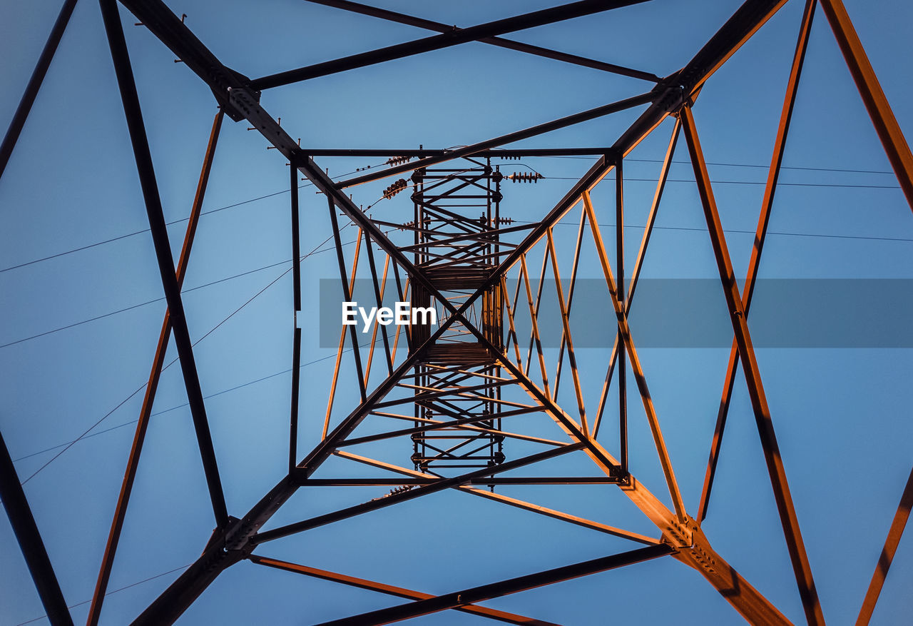 Low angle view of electricity pylon against clear sky