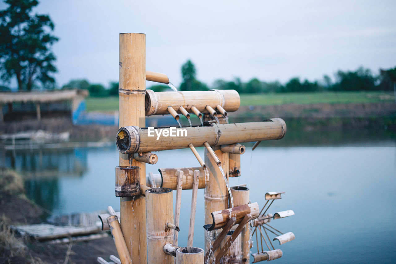 CLOSE-UP OF WOODEN POSTS IN LAKE