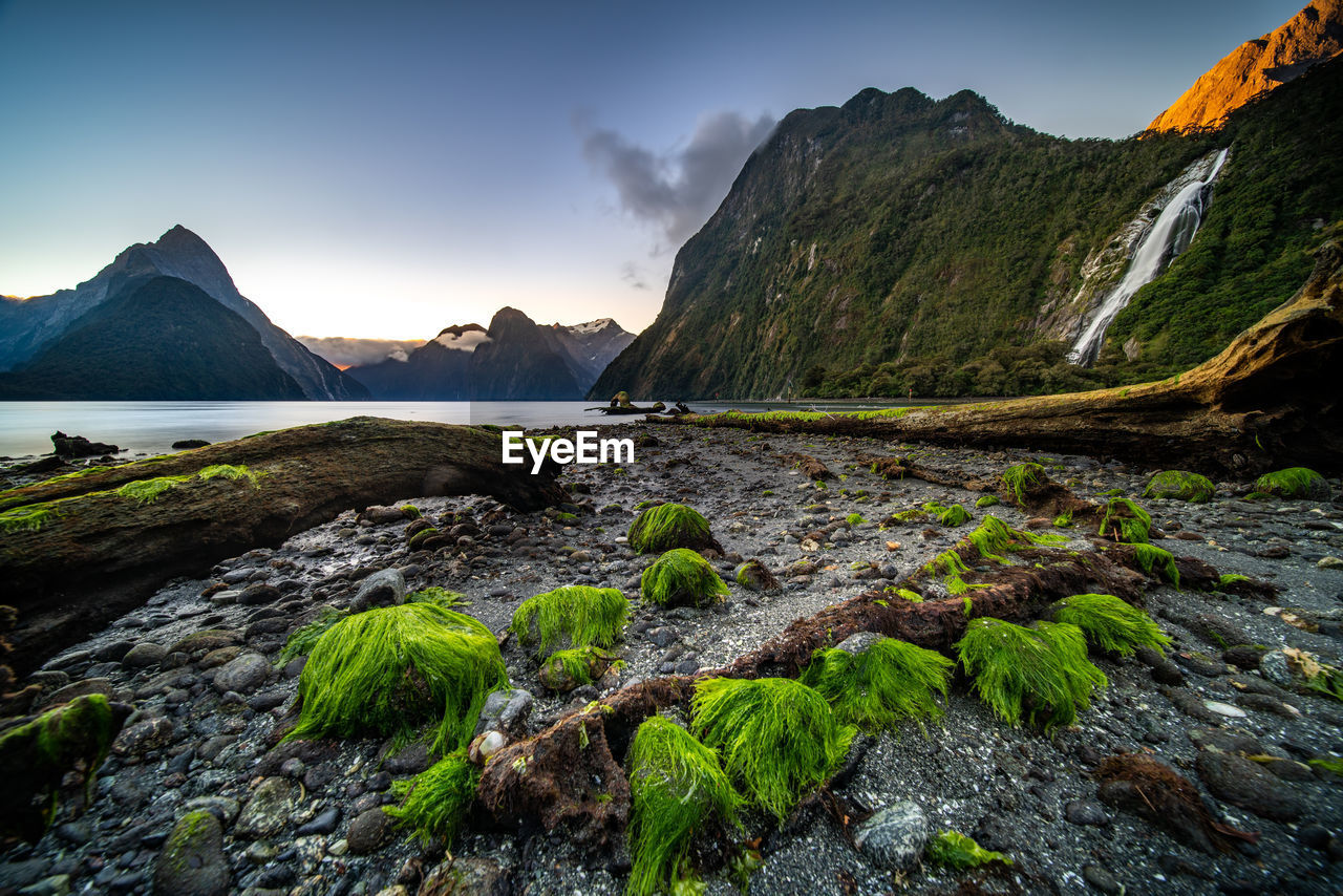 Scenic view of rocky mountains by sea against sky