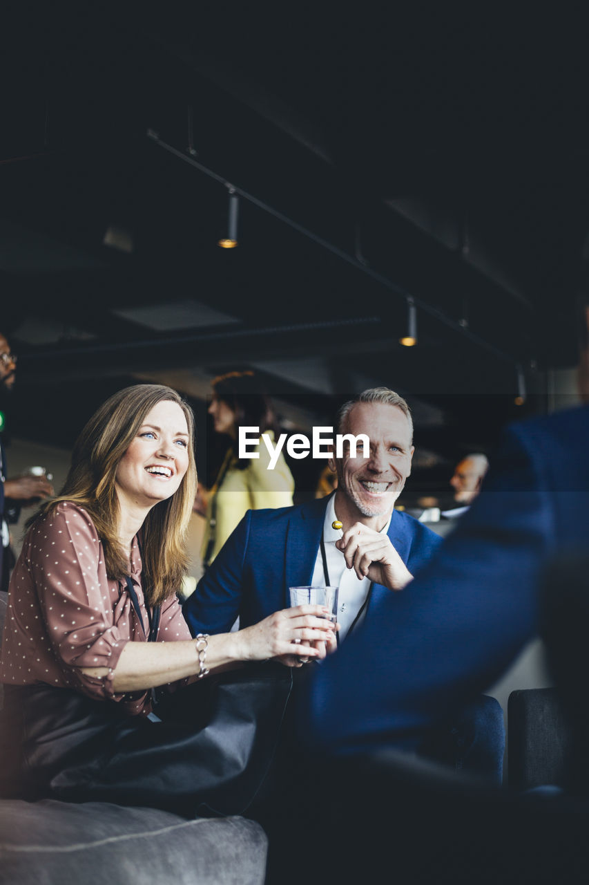 Smiling entrepreneurs sitting with coworker in office