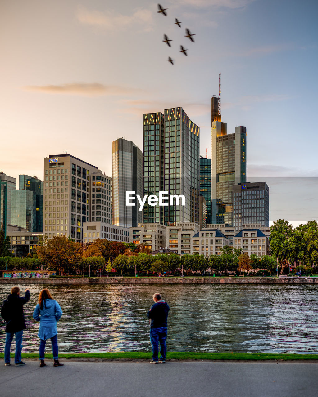 PEOPLE IN RIVER BY BUILDINGS AGAINST SKY