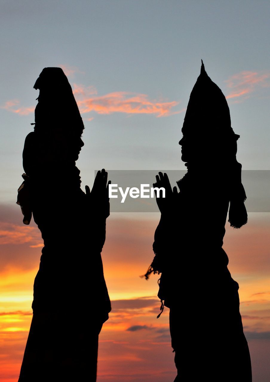 SILHOUETTE STATUE AGAINST ORANGE SKY