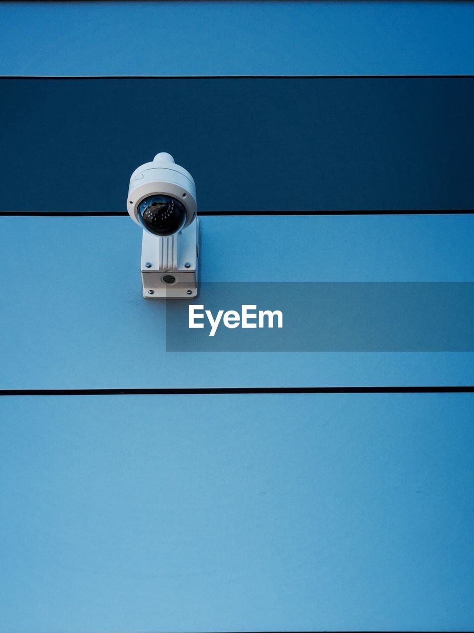 Low angle view of security camera on blue wall