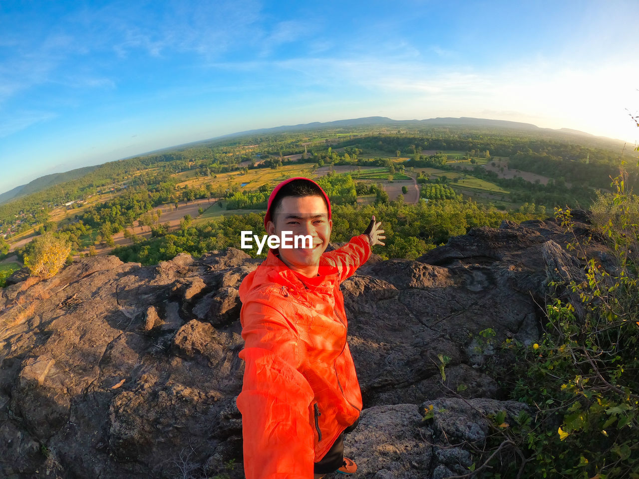 Portrait of smiling man standing on mountain against sky