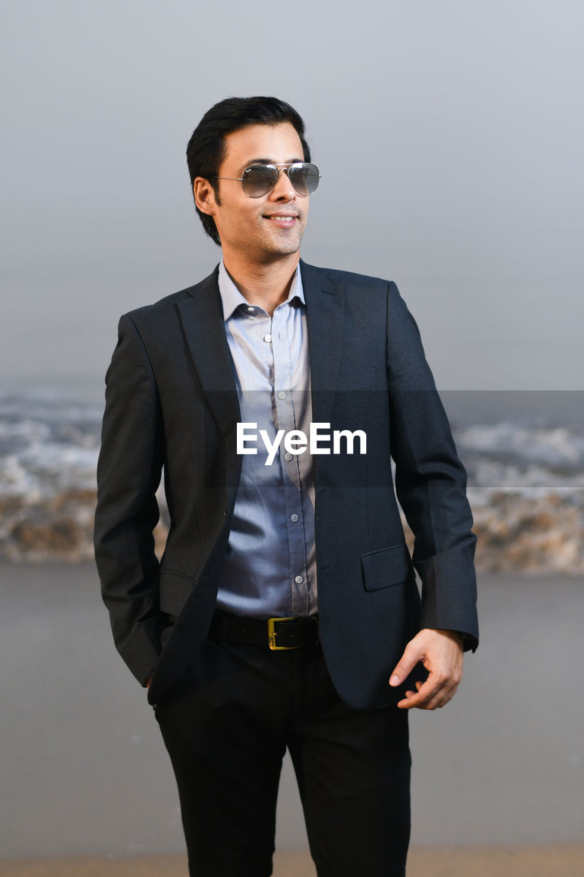 Young businessman standing at beach