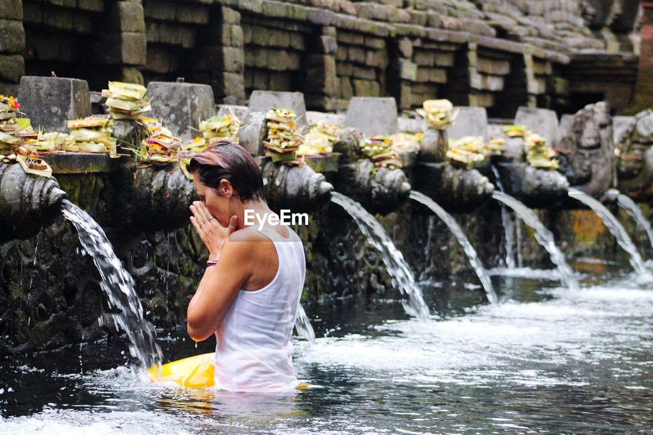 Side view of woman bathing at tirta empul temple