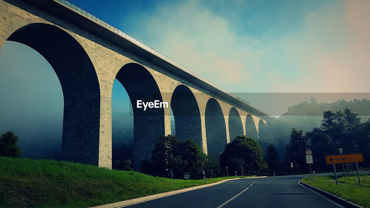 Road by bridge against sky