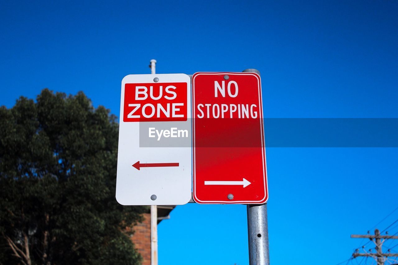 Low angle view of road signs against clear blue sky