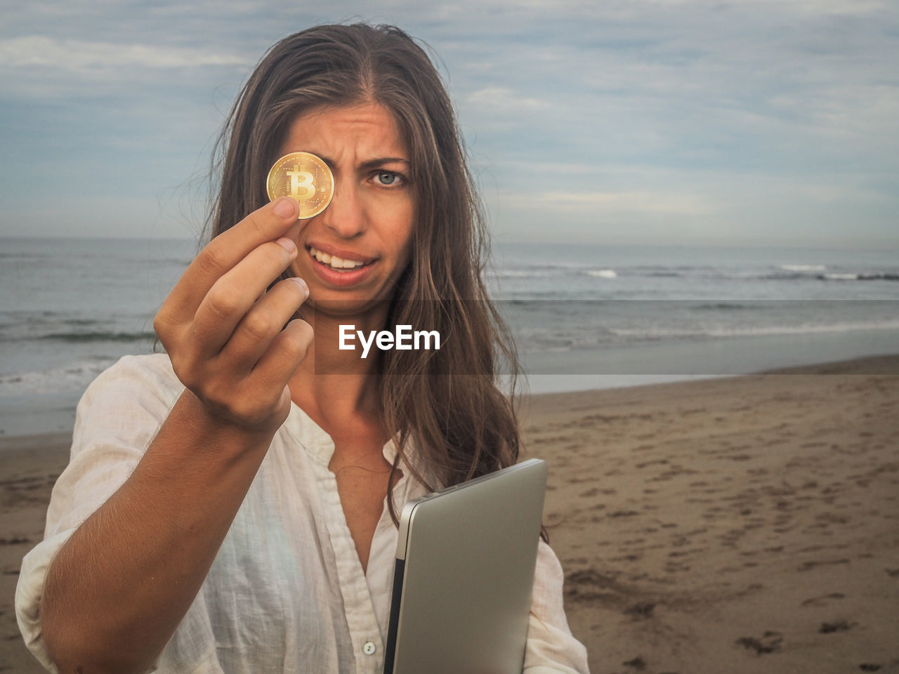 PORTRAIT OF YOUNG WOMAN USING SMART PHONE AT BEACH