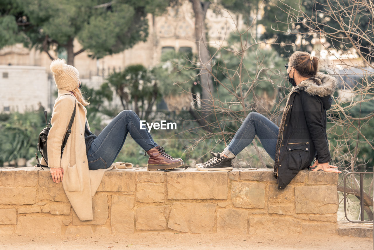 REAR VIEW OF COUPLE SITTING ON TREE