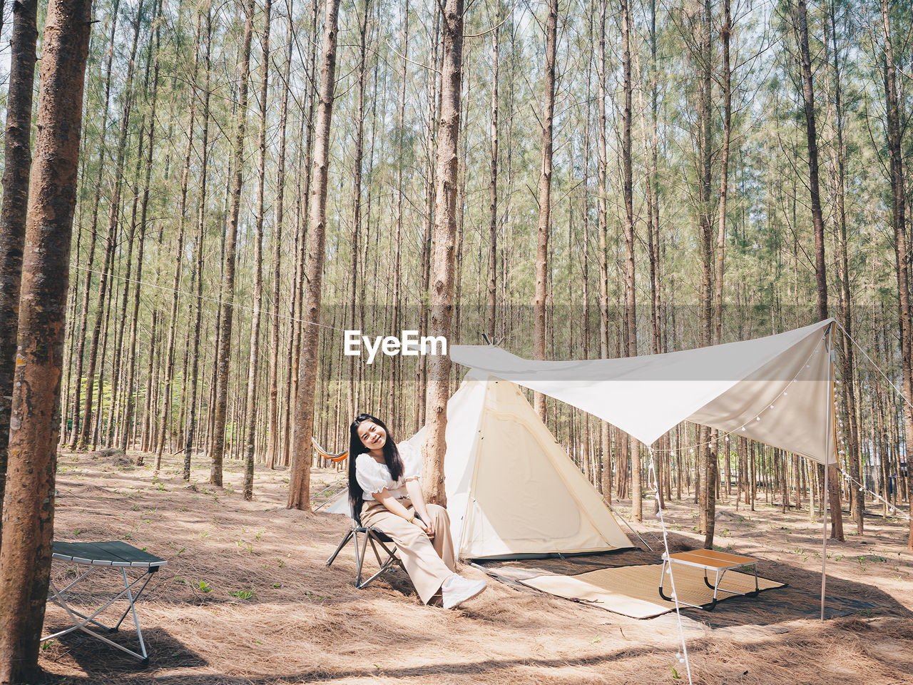 Happy asian teenage girl in front of camp tent. outdoor activity. 