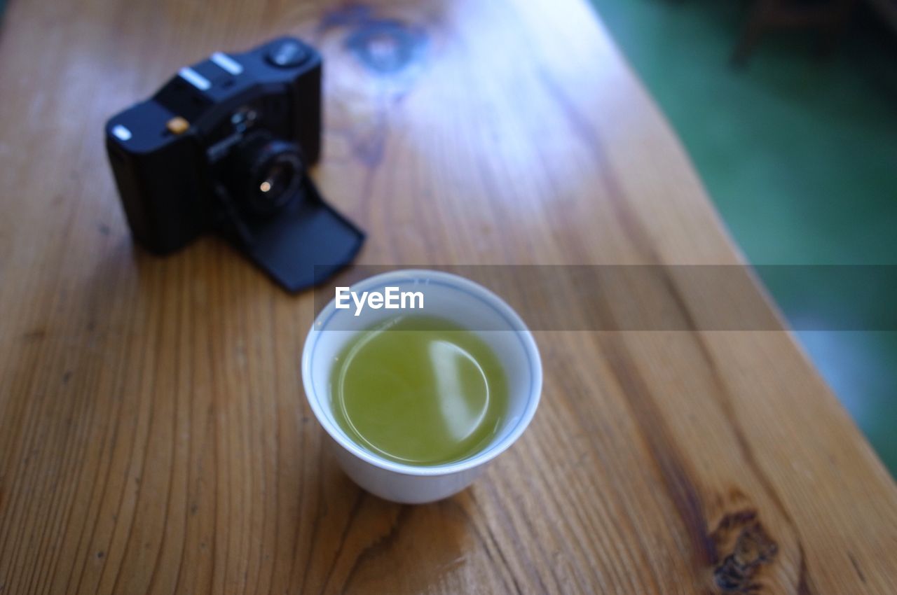 Close-up of green tea by camera on table