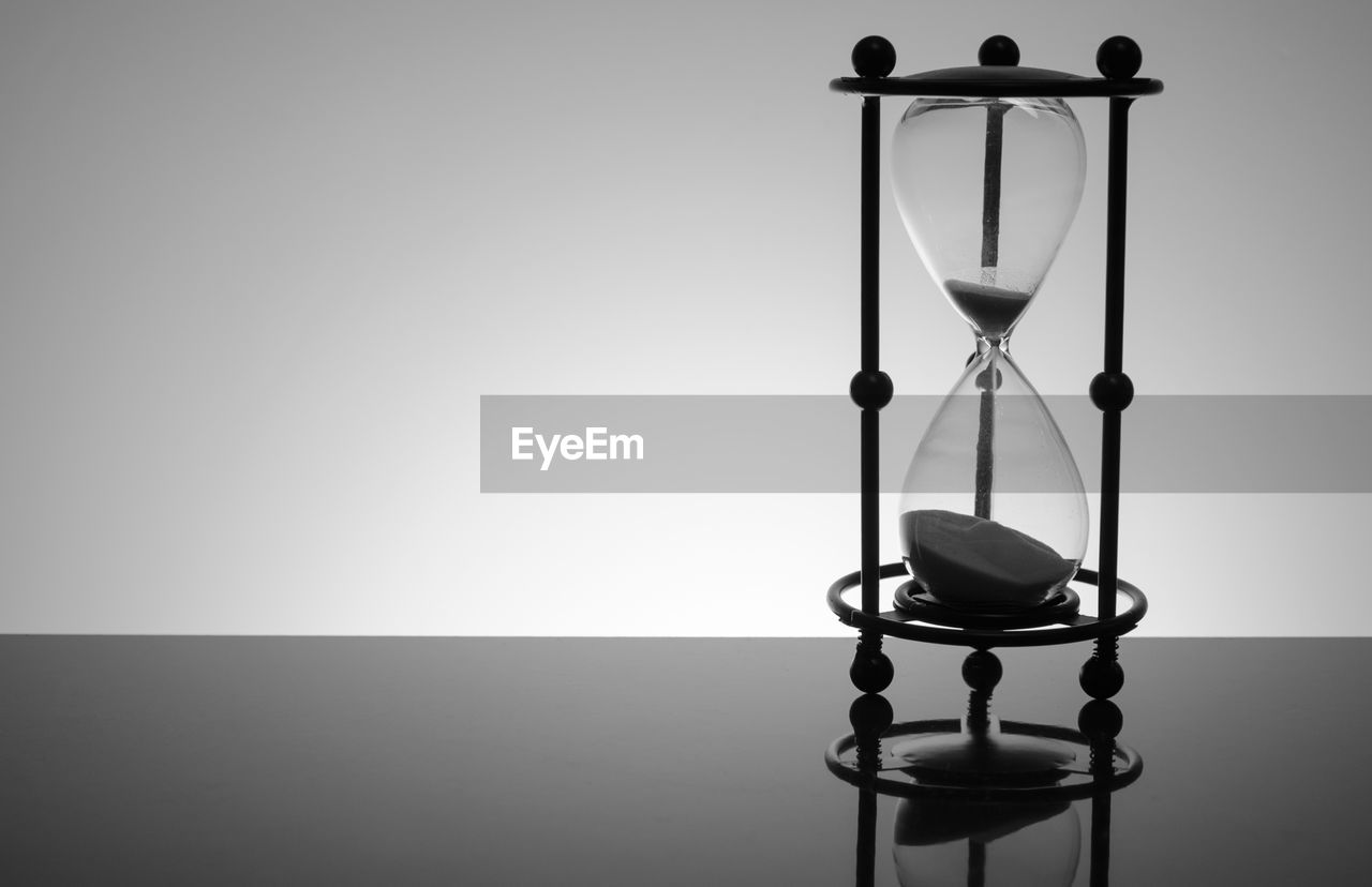 Close-up of hourglass on table against gray background