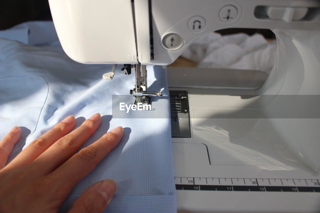 Cropped hand of woman stitching fabric on sewing machine