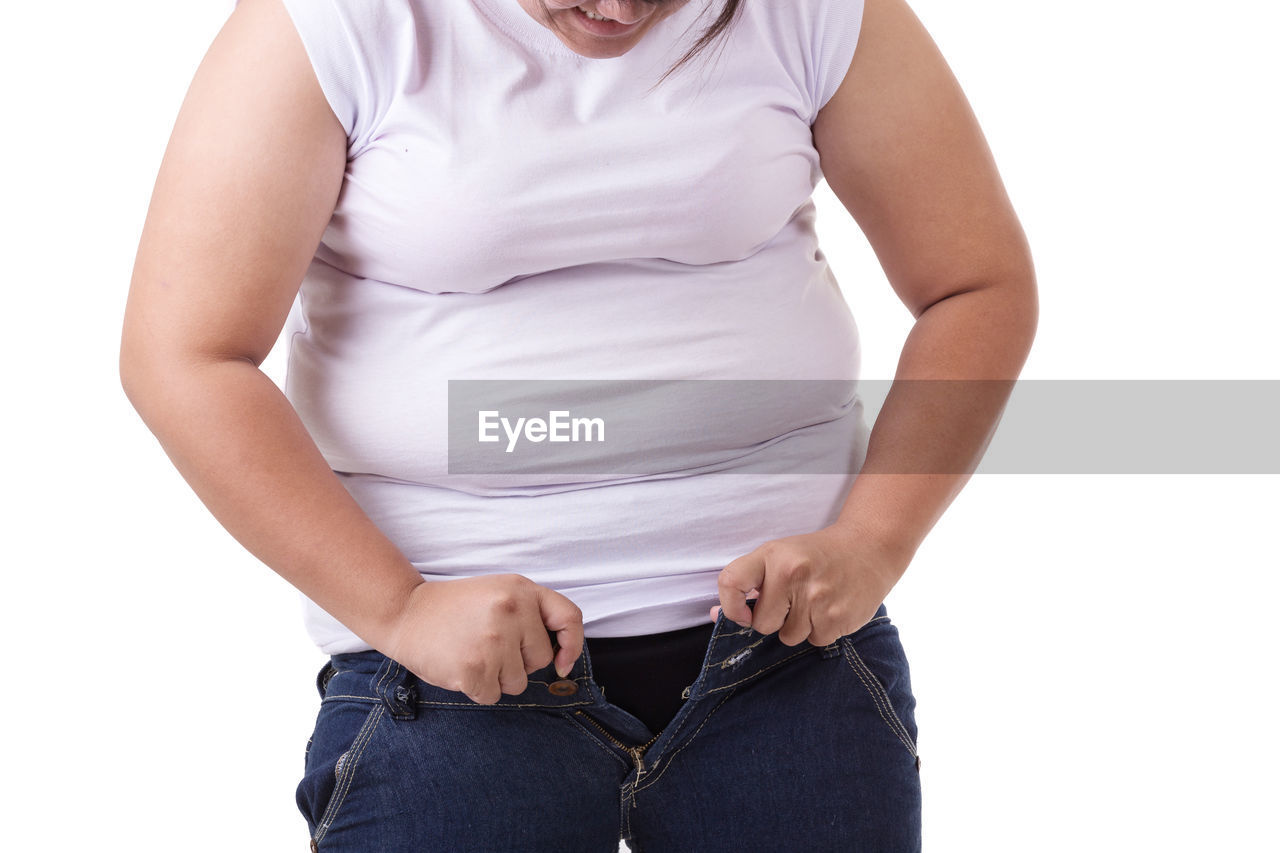 Midsection of overweight woman wearing jeans against white background