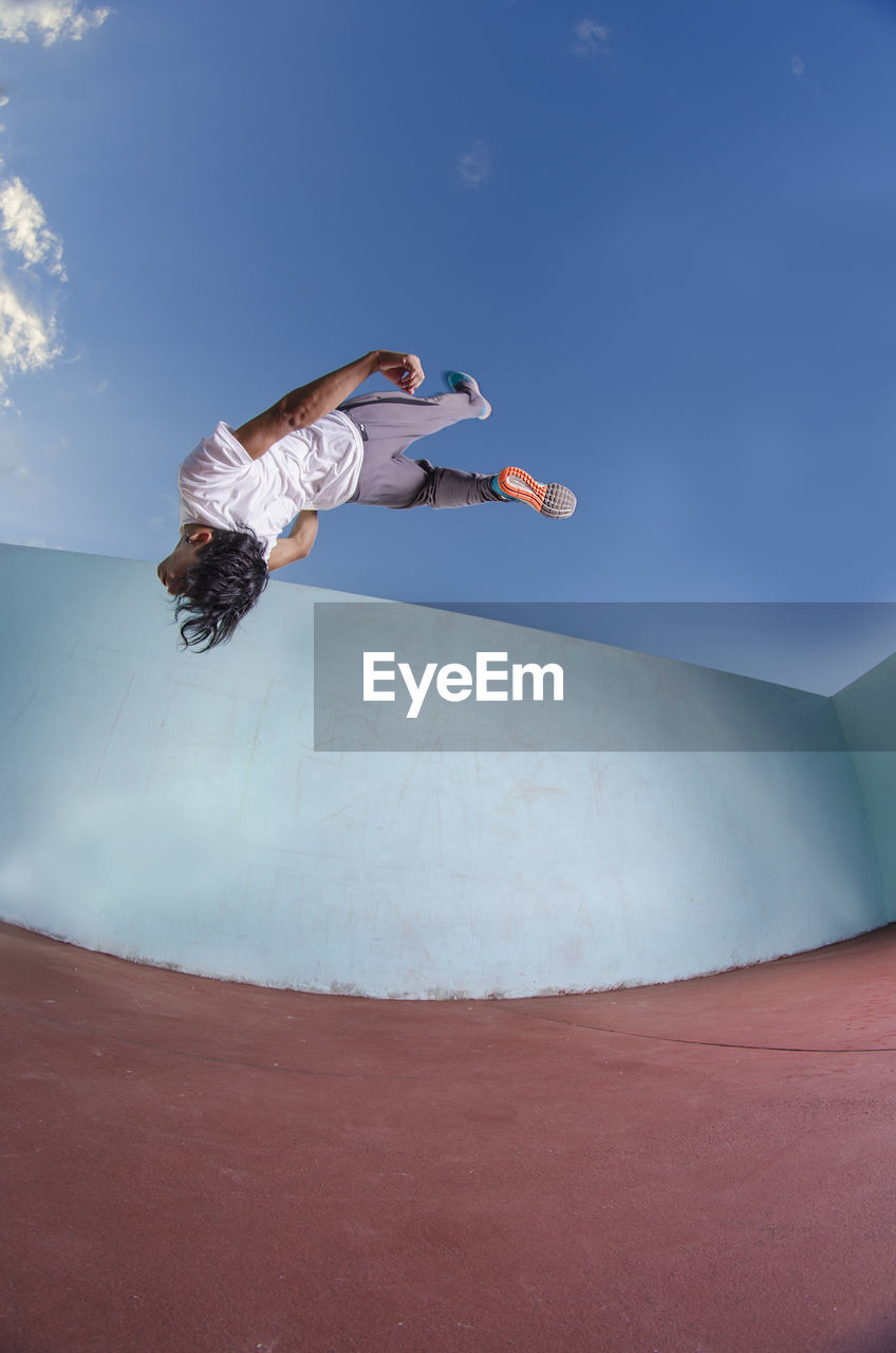 Low angle view of man jumping against sky