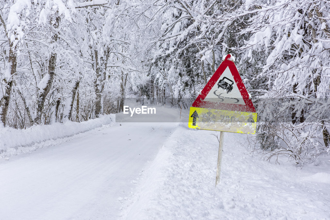 Road sign warns of ice and snow at winter