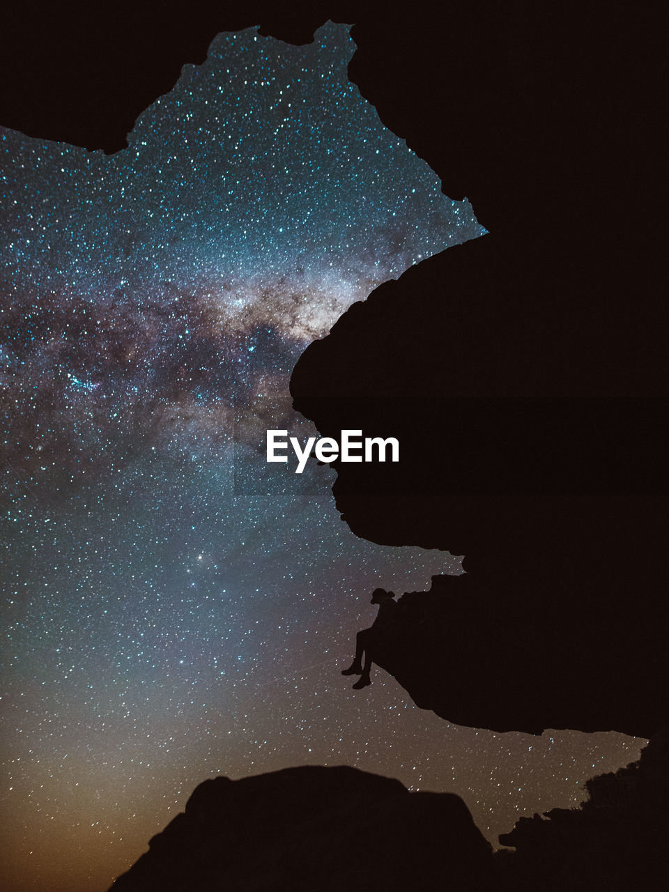Low angle view of silhouette woman sitting in mountain against sky at night