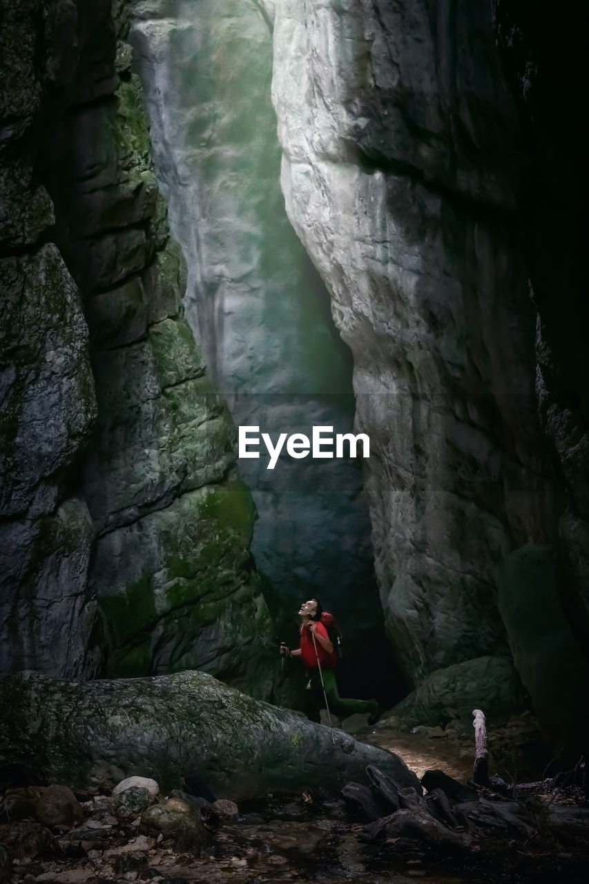 A man while inspecting a gorge, illuminated from above and surrounded by millenary rocks.