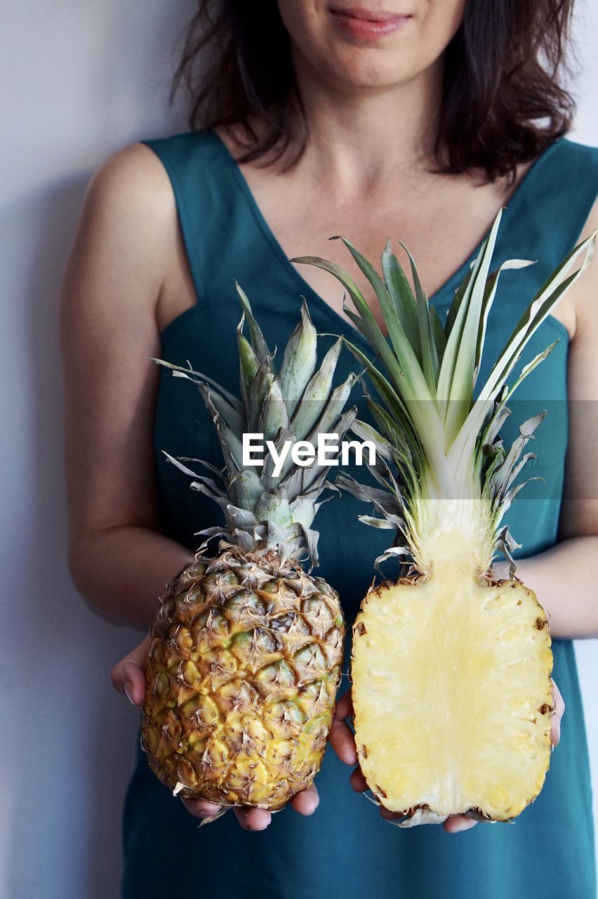 MIDSECTION OF WOMAN HOLDING FRUITS