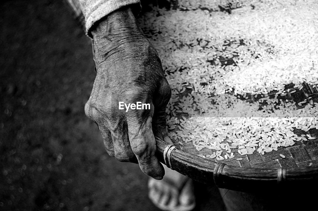 Cropped hand of person holding rice in basket