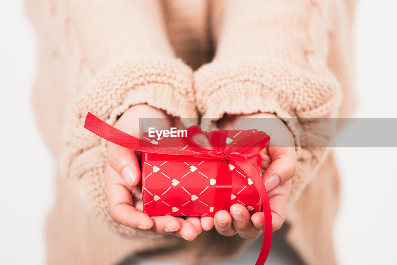 midsection of woman holding gift against wall