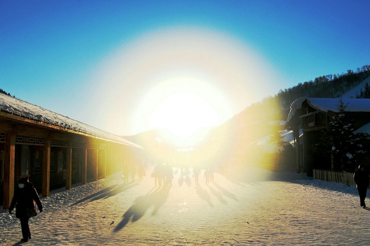 People on snowy walkway at sunny day