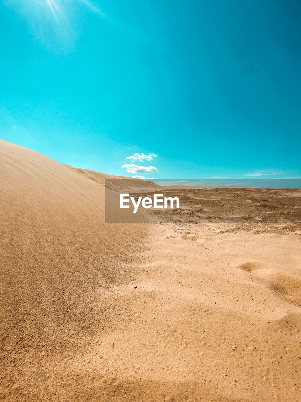 Sand dunes in desert against blue sky