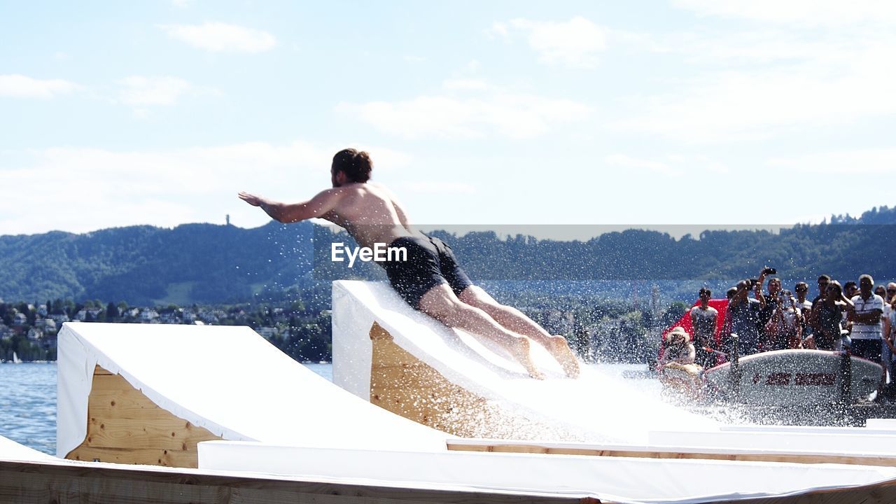 Full length of shirtless man against sky