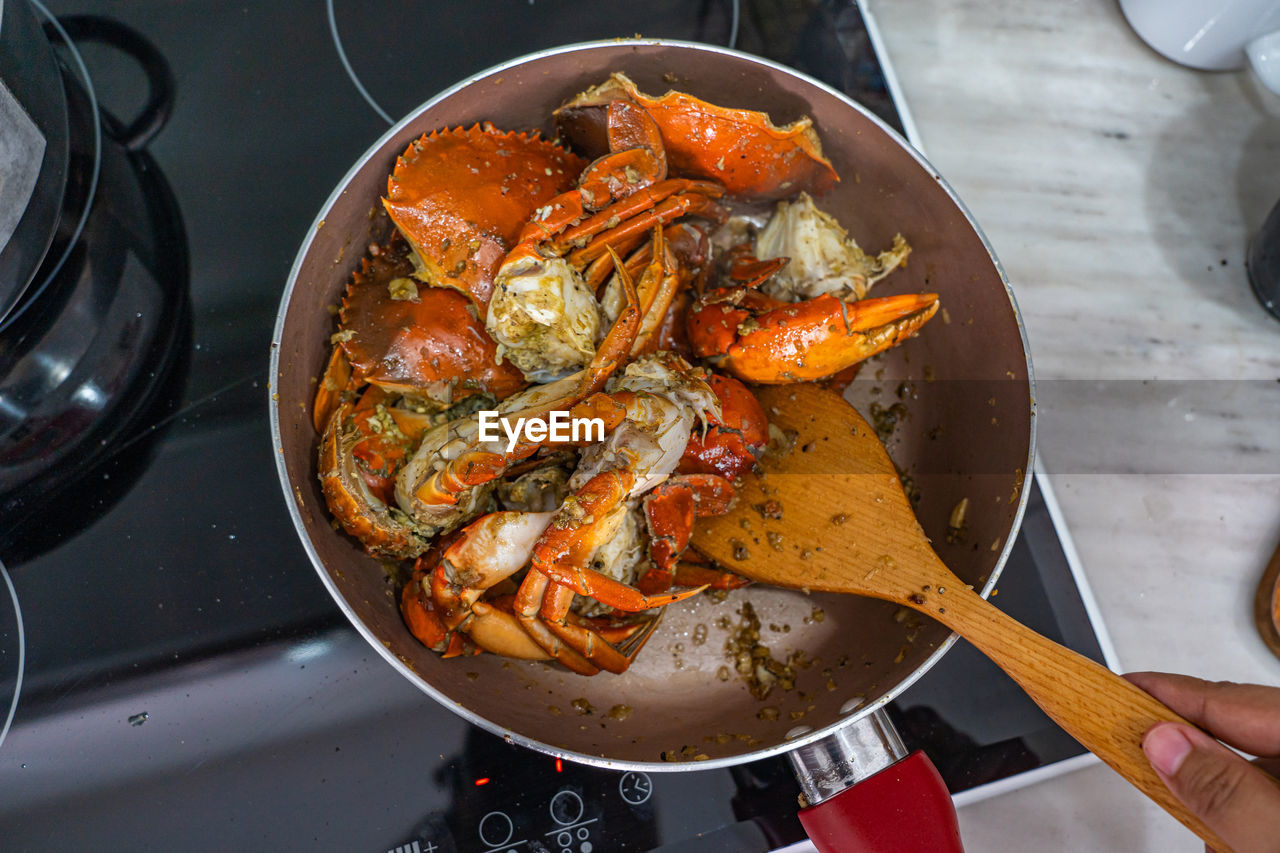 Overhead view photo of human cooking stir-fried crab with pepper