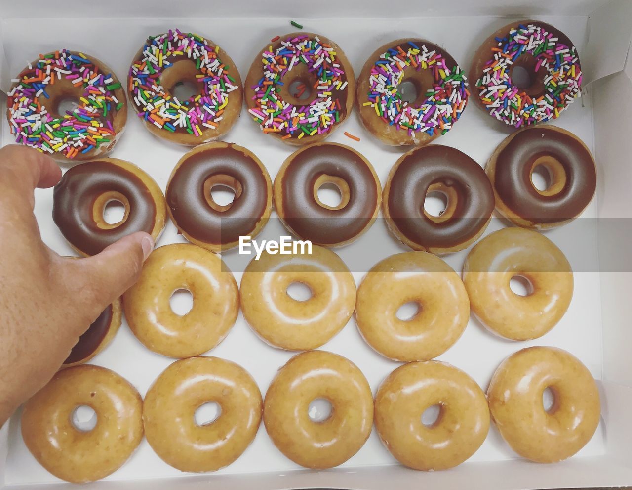 Cropped hand removing donut from box