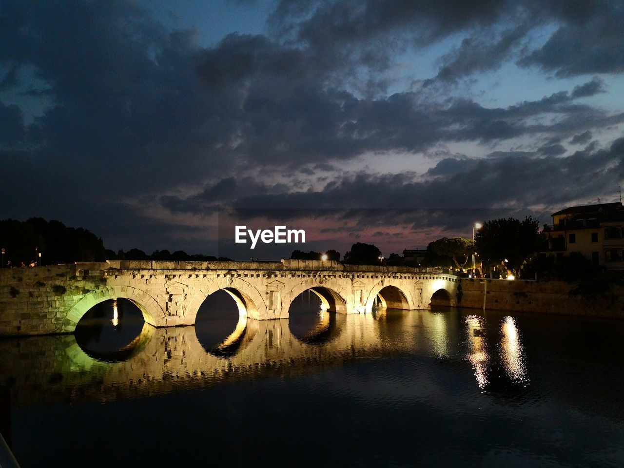 Arch bridge over river against sky during sunset