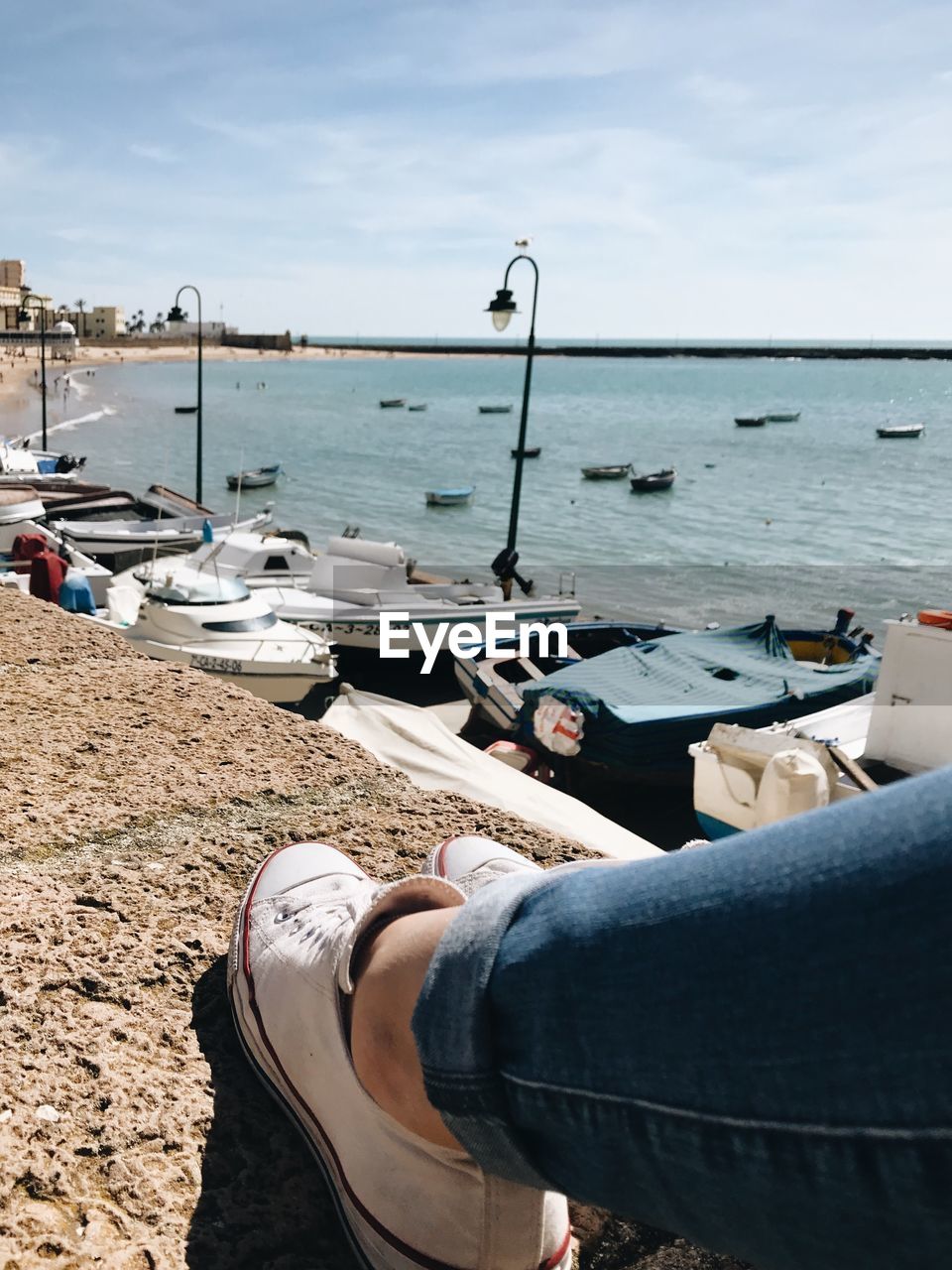 Low section of woman on retaining wall against sea