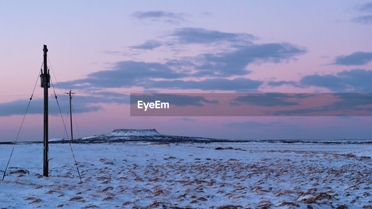 Pink sunrise over winter landscape with volcano