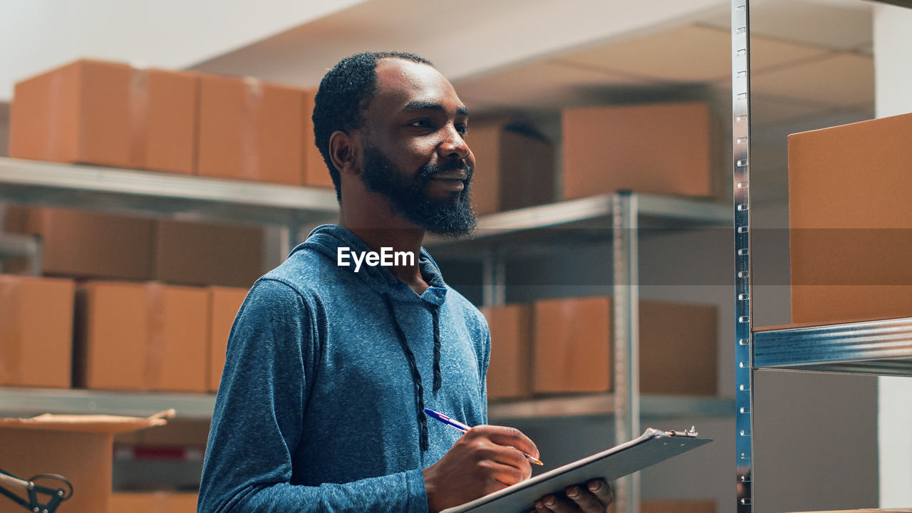 young man looking away while standing in office