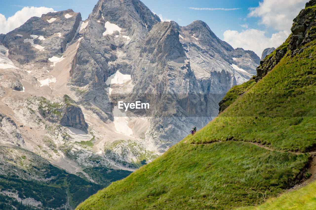 Man and woman riding their mountain bikes on footpath in the scenic dolomites, italy