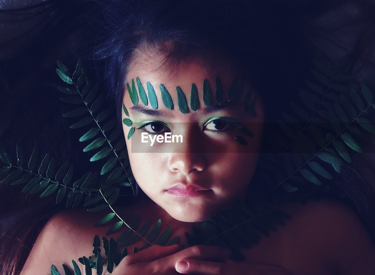 Close-up portrait of girl with leaves on face