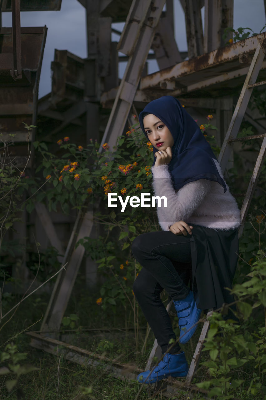 Portrait of young woman sitting by plants