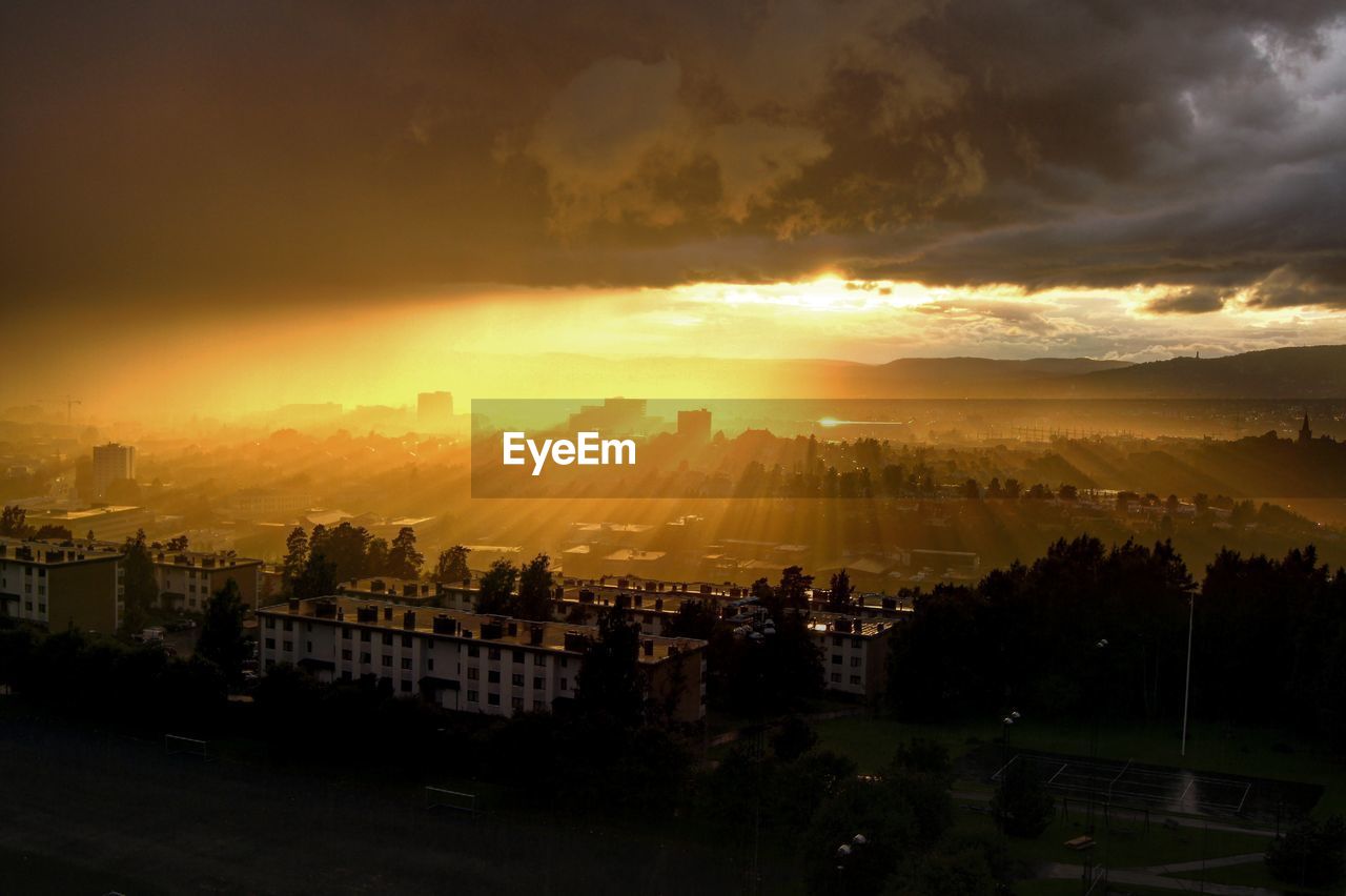 High angle view of cityscape against cloudy sky during sunset