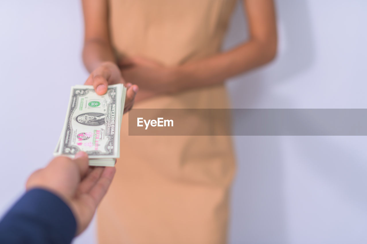 CLOSE-UP OF WOMAN HAND HOLDING PAPER OVER GRAY BACKGROUND