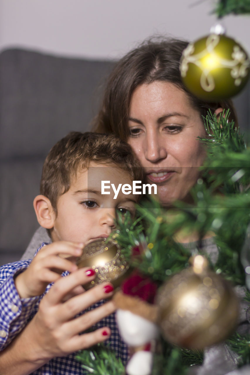 Mother and son decorating christmas tree at home