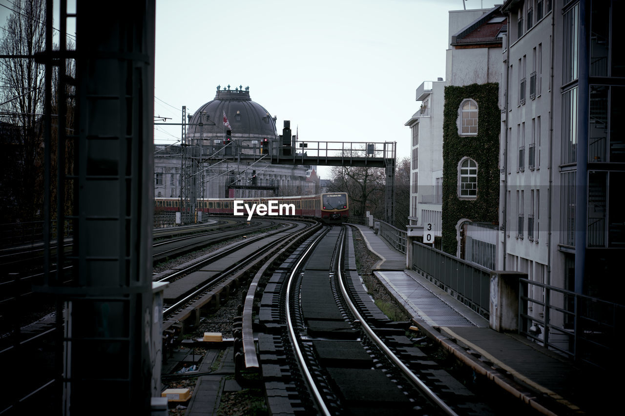 Railroad tracks amidst buildings in city against sky