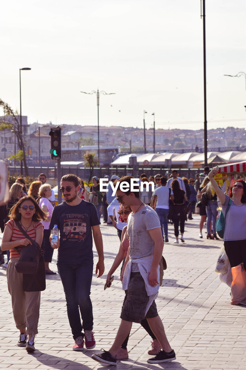 REAR VIEW OF PEOPLE WALKING ON STREET