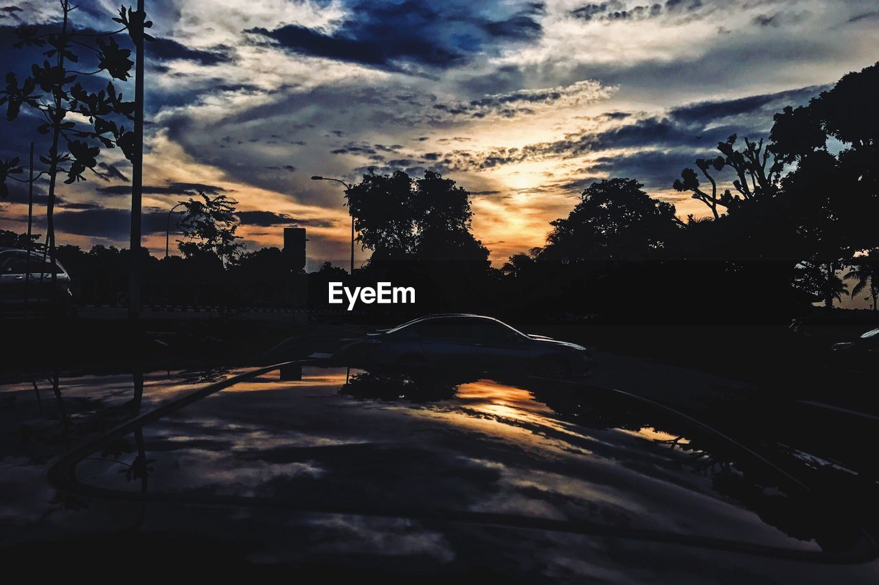 CAR ON ROAD AGAINST SKY AT SUNSET