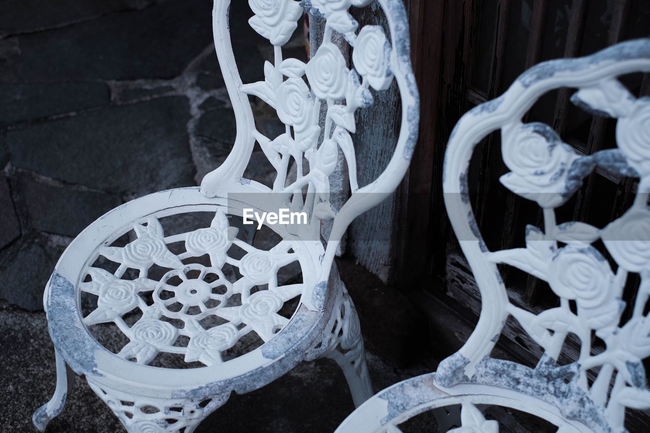 High angle view of old white empty chairs on footpath