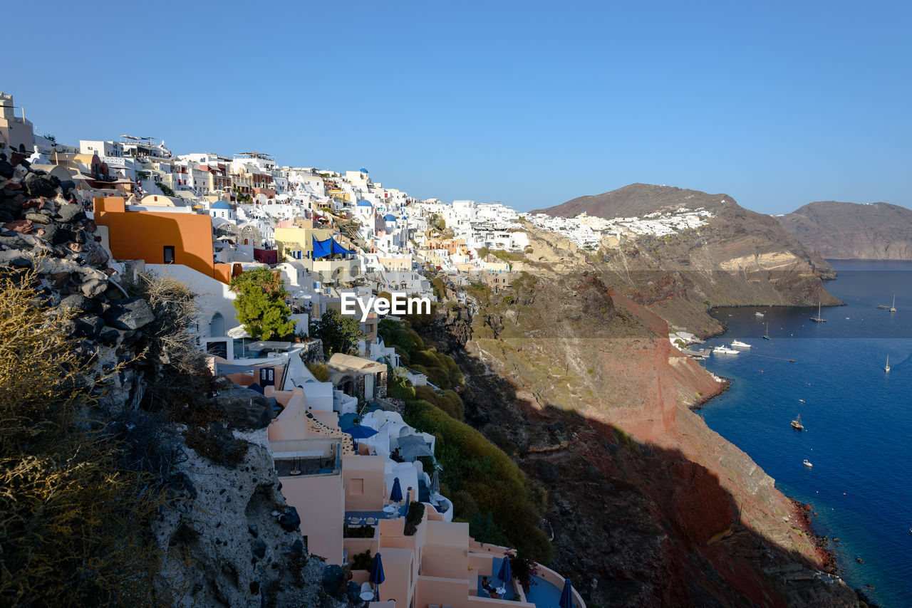 Town by sea against clear blue sky